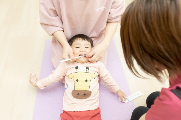 歯磨きをしてもらっている幼児